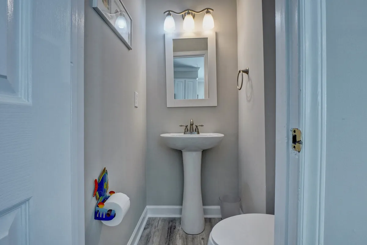 A well-lit bathroom featuring a modern sink, chrome faucet, large mirror, and updated light fixtures. The space feels fresh and functional, ideal for quick refreshes or personal grooming during group stays.